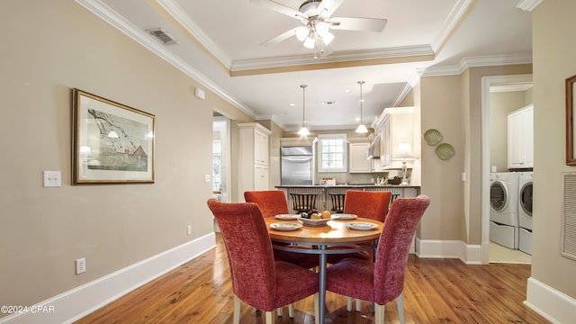 dining space with ornamental molding, light wood-type flooring, and washer and clothes dryer