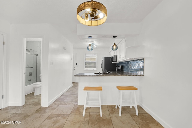 kitchen featuring decorative backsplash, white cabinetry, kitchen peninsula, a kitchen bar, and decorative light fixtures