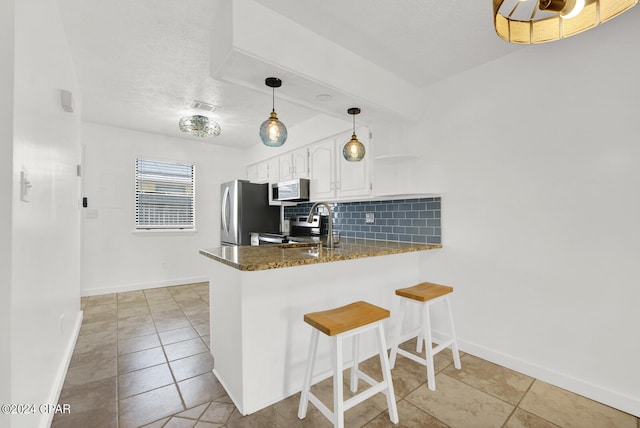 kitchen featuring backsplash, kitchen peninsula, white cabinetry, and stainless steel appliances