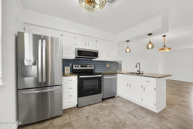 kitchen with appliances with stainless steel finishes, white cabinets, backsplash, kitchen peninsula, and decorative light fixtures