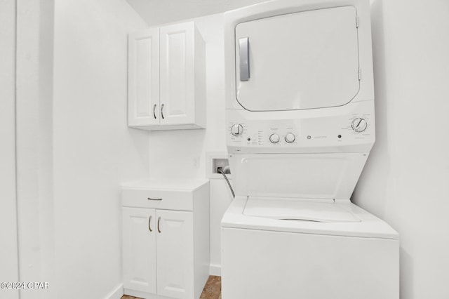 laundry room featuring cabinets and stacked washer / dryer