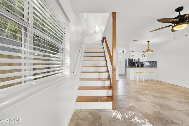 stairs featuring tile patterned flooring and ceiling fan