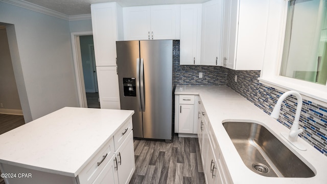 kitchen featuring stainless steel fridge, white cabinetry, tasteful backsplash, a center island, and sink