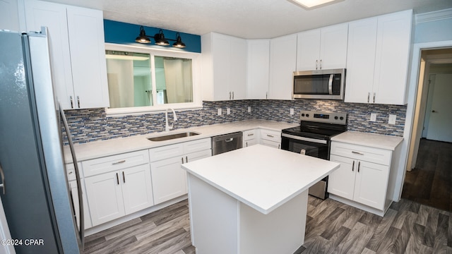 kitchen featuring a center island, sink, stainless steel appliances, and white cabinetry