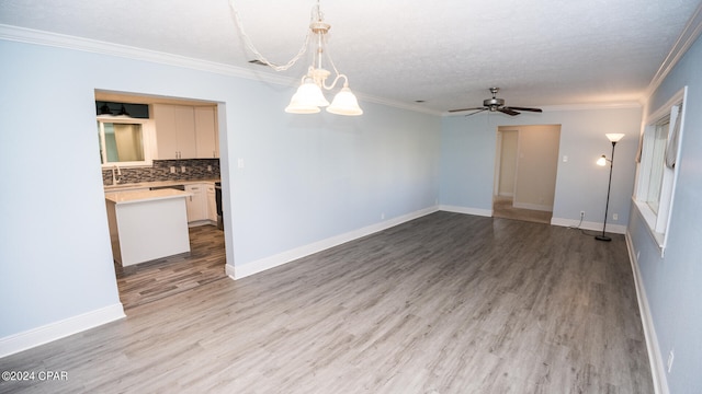 unfurnished room with a textured ceiling, ceiling fan with notable chandelier, ornamental molding, and light hardwood / wood-style flooring