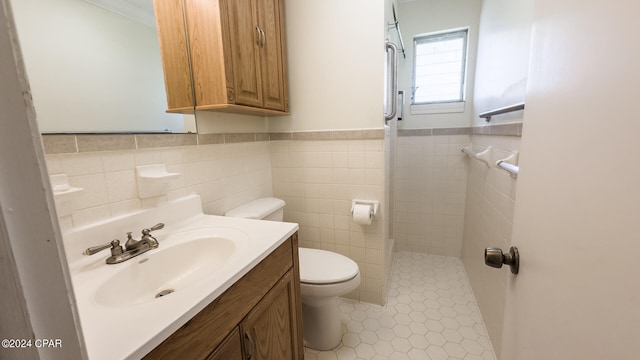 bathroom with tile walls, a shower, vanity, toilet, and tile patterned floors