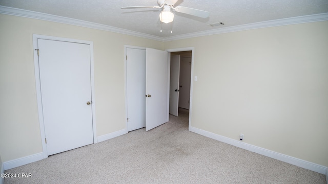 unfurnished bedroom featuring ornamental molding, ceiling fan, light colored carpet, and a textured ceiling