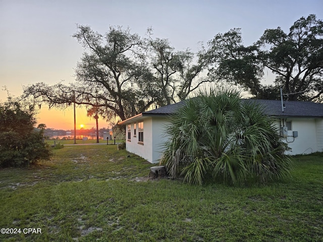 property exterior at dusk with a lawn