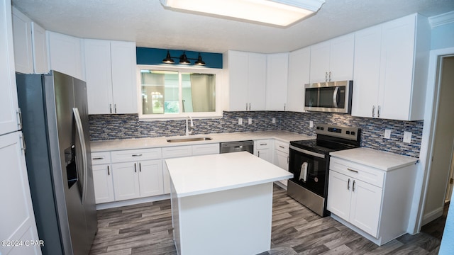 kitchen featuring appliances with stainless steel finishes, a kitchen island, sink, and white cabinets