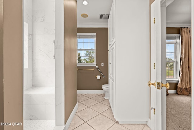 bathroom featuring ornamental molding, tile patterned flooring, toilet, and tiled shower