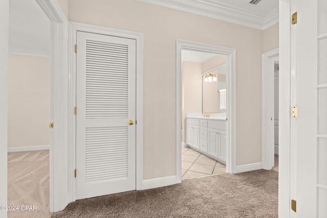 hallway with ornamental molding and light carpet