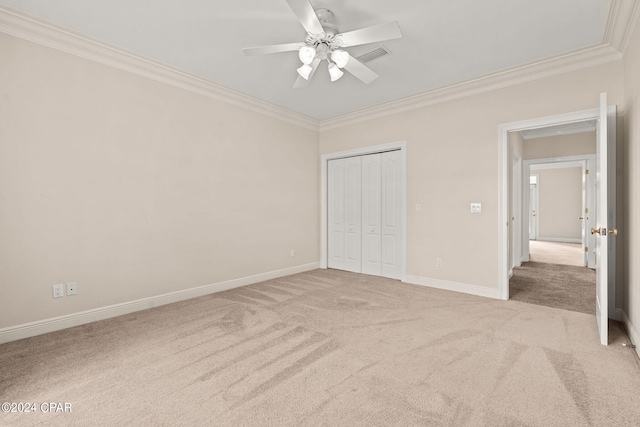 unfurnished bedroom featuring a closet, ceiling fan, light colored carpet, and crown molding