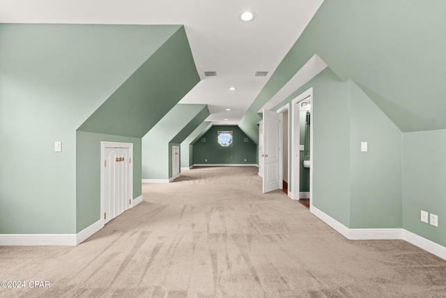 additional living space featuring light colored carpet and vaulted ceiling