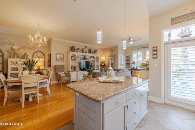 kitchen with light hardwood / wood-style floors, a kitchen island, plenty of natural light, and light stone counters