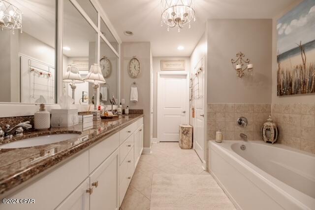 bathroom with a tub, tile patterned flooring, vanity, and a notable chandelier