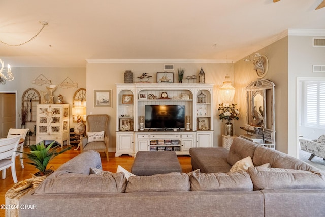 living room featuring hardwood / wood-style floors, an inviting chandelier, and ornamental molding