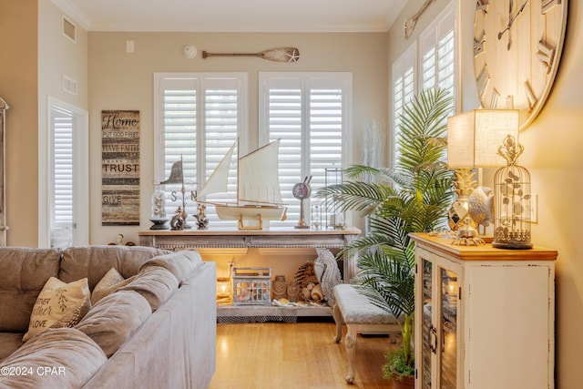 living area with light wood-type flooring and ornamental molding