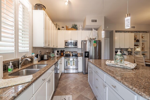 kitchen featuring white cabinetry, sink, pendant lighting, stone countertops, and appliances with stainless steel finishes