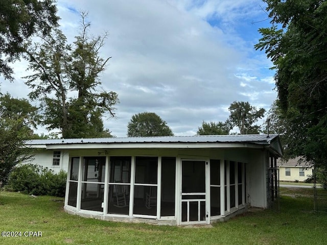 rear view of property featuring a sunroom and a lawn