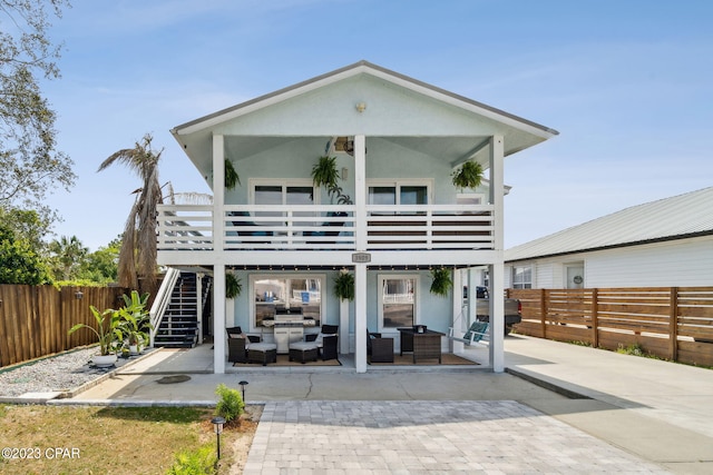 back of property featuring a balcony, an outdoor living space, and a patio area