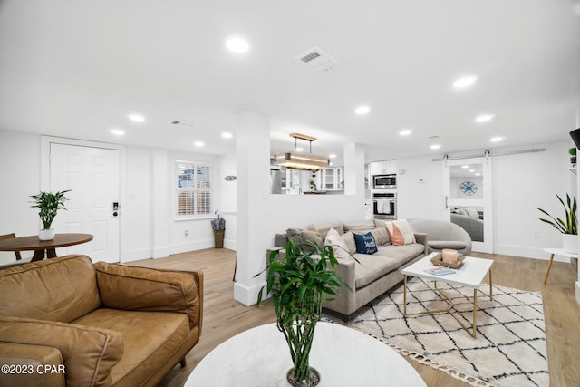 living room featuring light hardwood / wood-style floors and a barn door