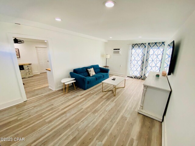 living area featuring light hardwood / wood-style floors and a wall unit AC