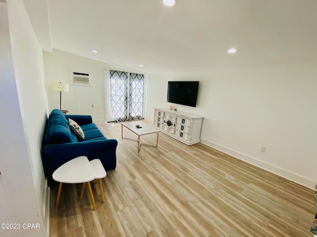 living room with light hardwood / wood-style floors and a wall unit AC