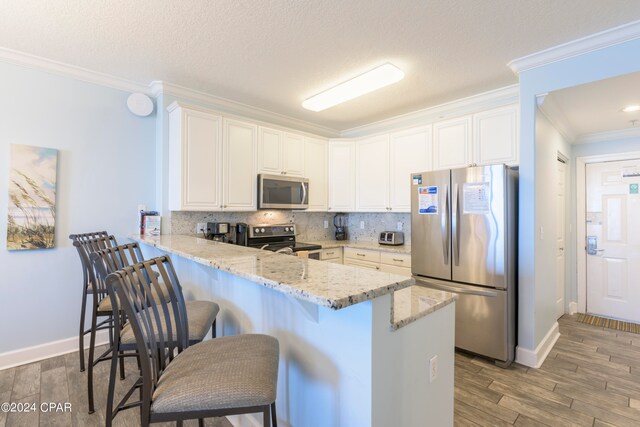 kitchen featuring appliances with stainless steel finishes, kitchen peninsula, a breakfast bar area, and hardwood / wood-style flooring