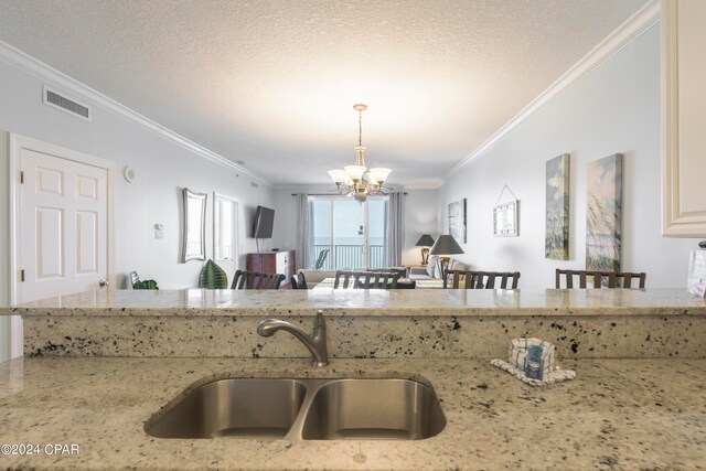 kitchen featuring sink, ornamental molding, decorative light fixtures, an inviting chandelier, and light stone countertops