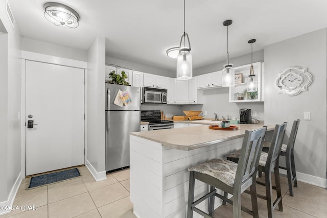 kitchen with a breakfast bar, white cabinets, kitchen peninsula, stainless steel appliances, and light tile patterned floors