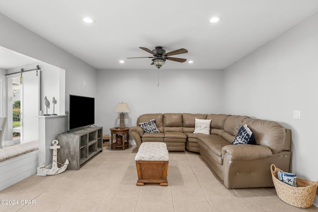 tiled living room featuring a barn door and ceiling fan