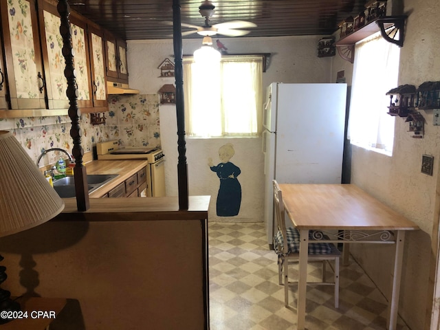 kitchen with white refrigerator, kitchen peninsula, ceiling fan, sink, and electric range