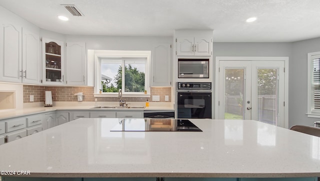 kitchen with white cabinets, black appliances, a kitchen island, and sink