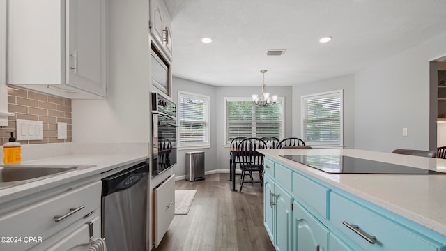 kitchen featuring white cabinetry, blue cabinetry, black appliances, light hardwood / wood-style flooring, and a chandelier