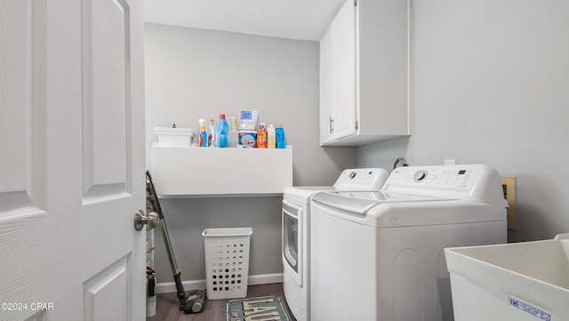 clothes washing area featuring washer and clothes dryer, hardwood / wood-style floors, sink, and cabinets