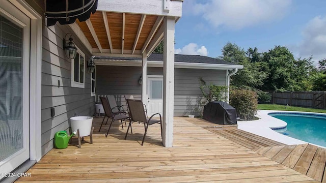 wooden deck with a fenced in pool and area for grilling