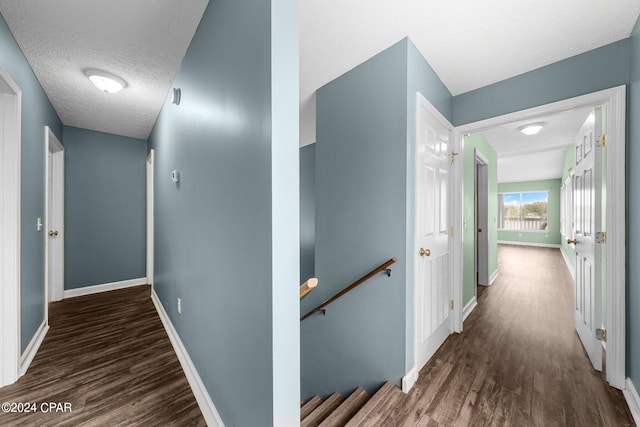 hallway with a textured ceiling and dark hardwood / wood-style floors