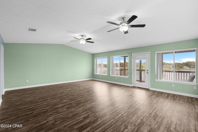 empty room with a textured ceiling, lofted ceiling, dark wood-type flooring, and ceiling fan