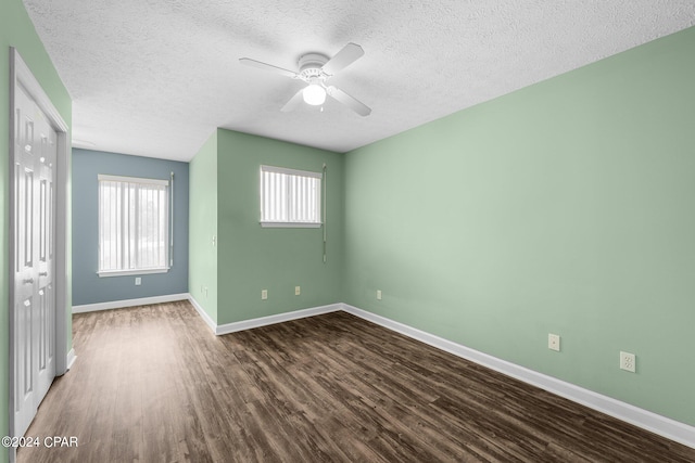 empty room featuring a textured ceiling, ceiling fan, and dark wood-type flooring