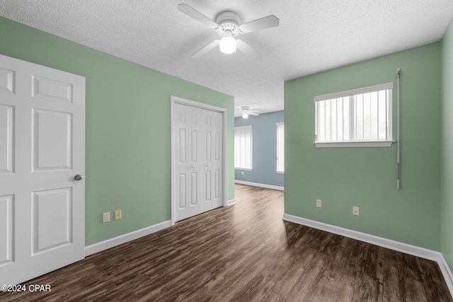 unfurnished bedroom with a closet, ceiling fan, dark wood-type flooring, and a textured ceiling