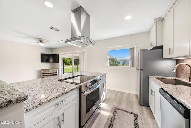 kitchen featuring white cabinets, light hardwood / wood-style flooring, light stone countertops, appliances with stainless steel finishes, and island exhaust hood