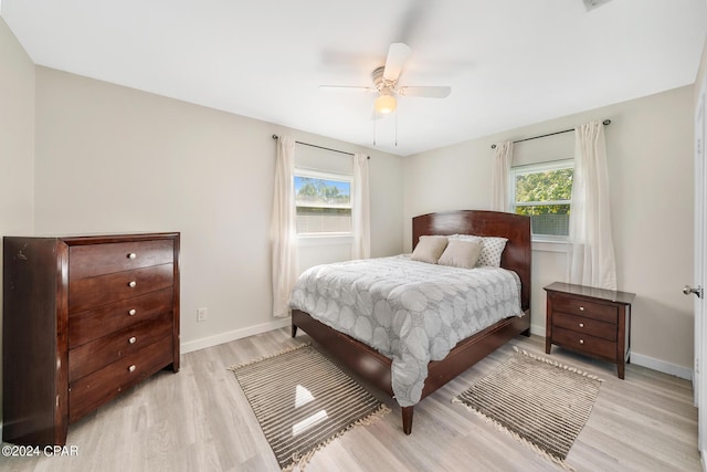 bedroom with multiple windows, ceiling fan, and light hardwood / wood-style floors