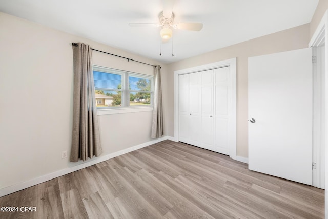 unfurnished bedroom featuring ceiling fan, a closet, and light wood-type flooring