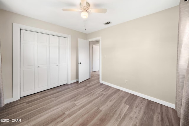 unfurnished bedroom featuring ceiling fan, light wood-type flooring, and a closet