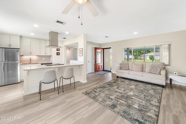 living room with ceiling fan, light hardwood / wood-style flooring, and sink