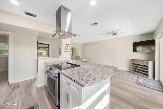 kitchen featuring white cabinetry, electric range, a wealth of natural light, island exhaust hood, and light hardwood / wood-style floors