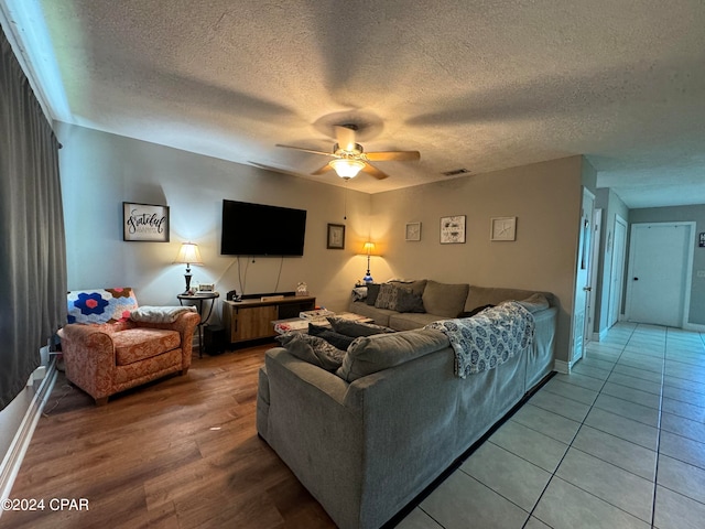 living room with ceiling fan, hardwood / wood-style flooring, and a textured ceiling