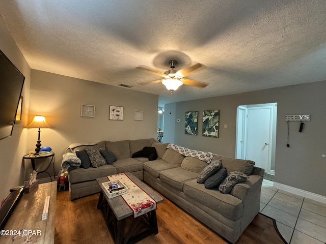 living room with ceiling fan, a textured ceiling, and hardwood / wood-style floors