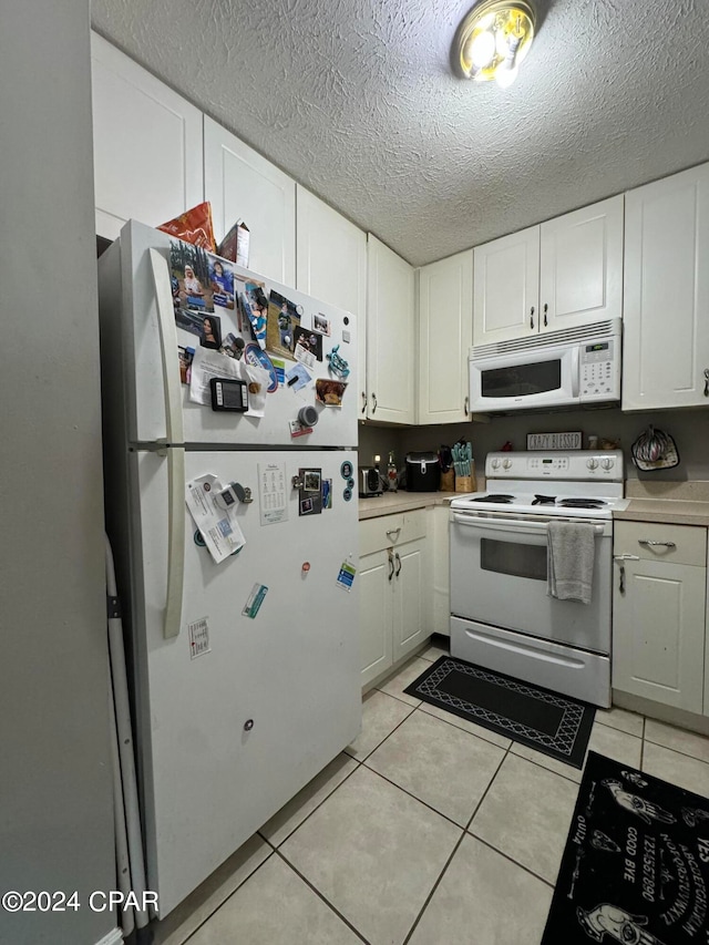 kitchen featuring white appliances, light tile patterned floors, and white cabinets