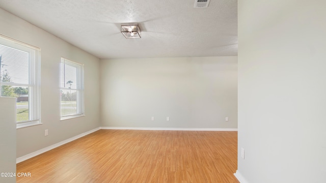 unfurnished room featuring a textured ceiling and light hardwood / wood-style flooring